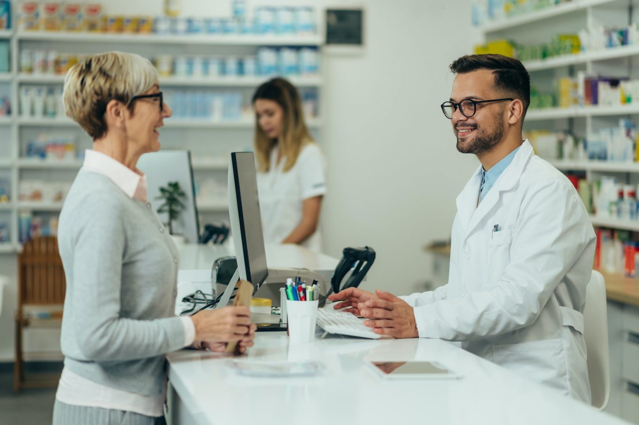 young-male-pharmacist-giving-prescription-medications-to-senior-female-customer-in-a-pharmacy.jpg